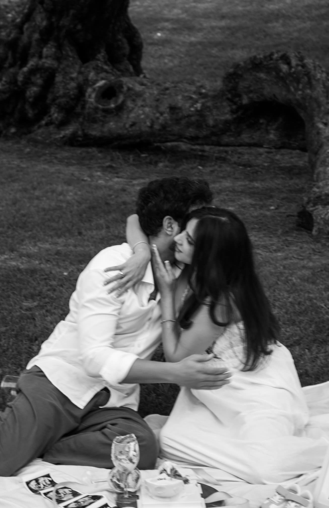 Black and white candid of a couple mid-embrace at a picnic